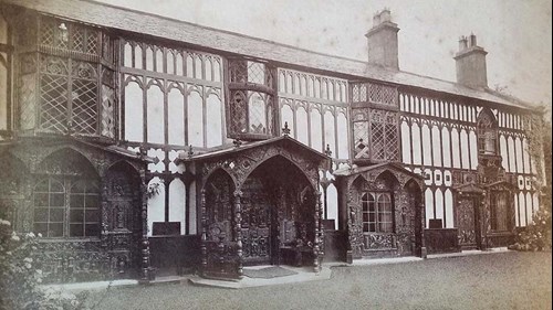 Sepia photograph of a medieval style large house, with several intricately detailed doorway arches